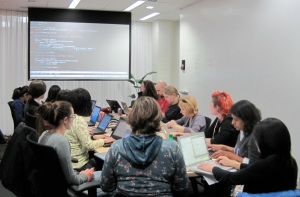 A breakout group at the Boston Python Workshop work at laptops around a table