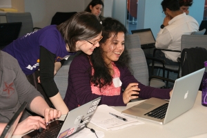 An instructor looks at a student's laptop at the Boston Python Workshop